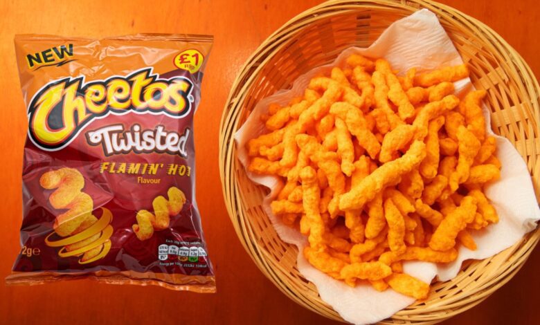 Bag and bowl of Twisted Cheetos on orange background.