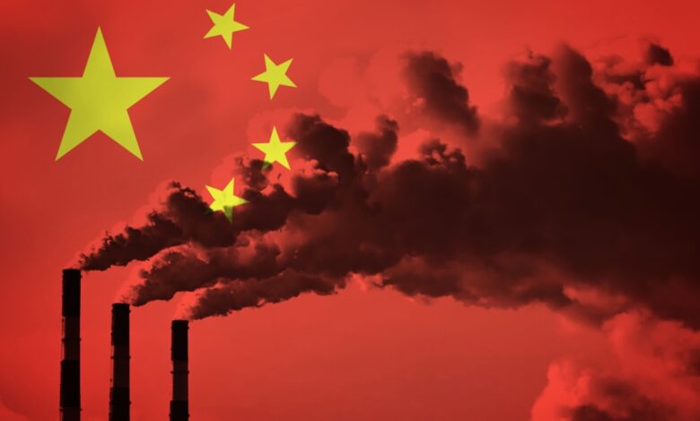 Three industrial smoke stacks in front of the flag of China.