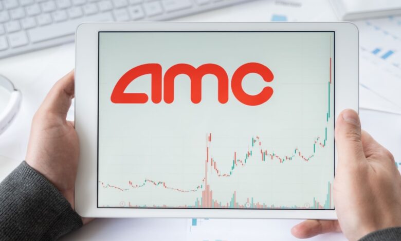 Man's hands hold white tablet with AMC Entertainment stock chart on it.
