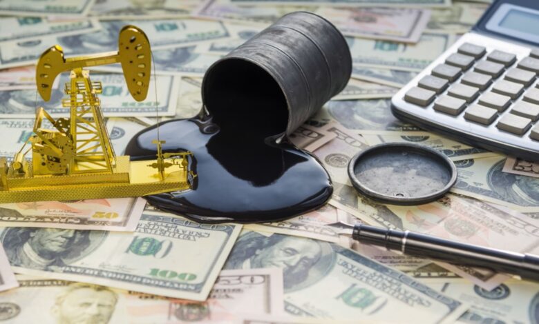 Small barrel spills oil across spread out dollar bills.