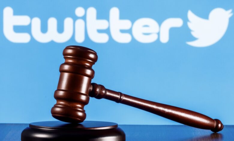 A judges gavel rests on a sound block in front of a blue background featuring the Twitter logo and text.
