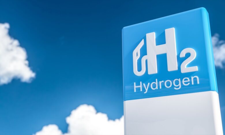 Blue and white H2 Hydrogen sign with blue sky and clouds in the background.