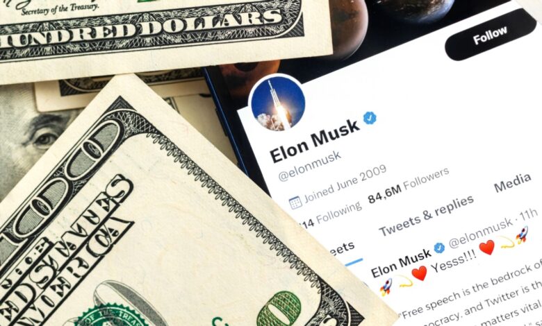 A smartphone displays Elon Musk’s Twitter profile with 84.6 million followers, surrounded by several U.S. hundred-dollar bills.