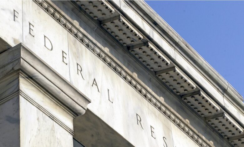 Close-up view of the exterior facade of the Federal Reserve building with engraved lettering, featuring classic marble architecture under a clear blue sky, symbolizing U.S. central banking system, monetary policy authority, and economic regulation.