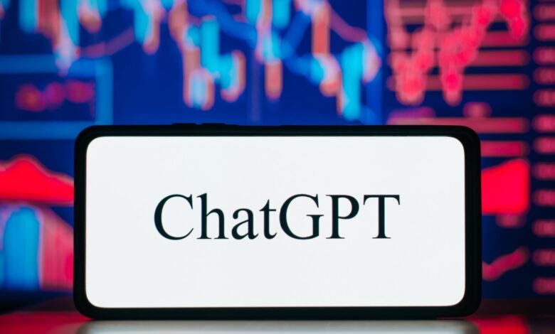 A smartphone screen displays the word "ChatGPT" in black text on a white background. Behind the phone is a colorful digital background featuring red and blue financial charts and graphs, suggesting a connection between AI and finance or data analysis.