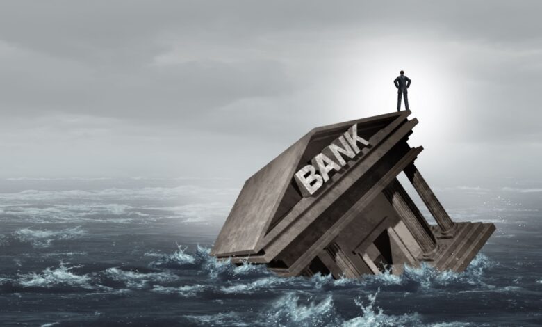 Man stands on financial bank sinking in ocean.