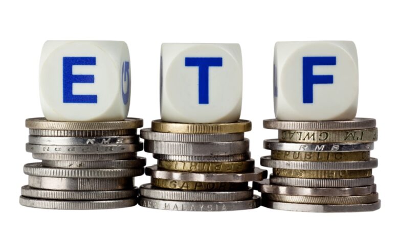 ETF investment concept with dice spelling 'ETF' placed on stacks of international coins, representing exchange-traded funds and global investing.