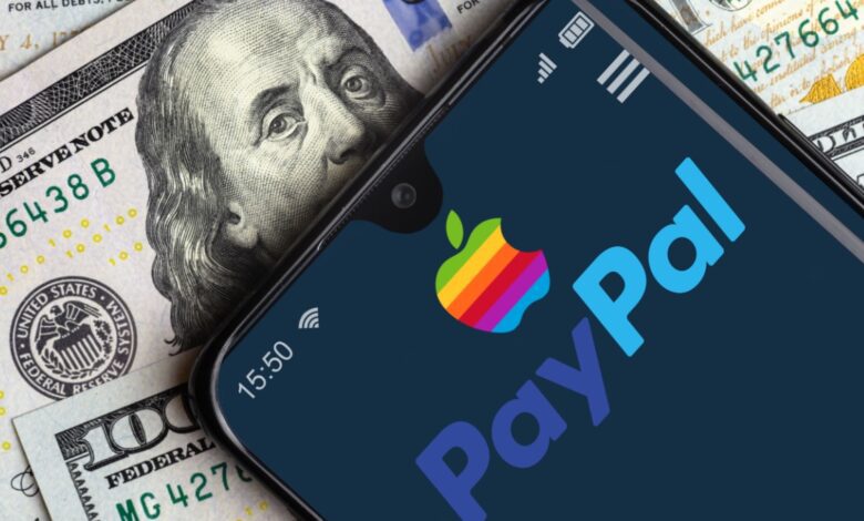 Smartphone displaying PayPal and Apple logos over a background of US hundred-dollar bills, symbolizing digital payments and financial technology integration.