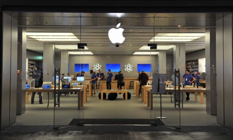 Shoppers inside glass Apple store.