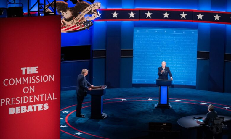 Joe Biden and Donald Trump on stage during the first 2020 Presidential election debate, standing at podiums with the Commission on Presidential Debates sign in the background.