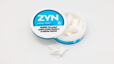 A half open tin of Philip Morris' Cool Mint flavored ZYN nicotine pouches set on an off-white colored background.