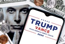 Elon Musk peers through an opening in a background of money next to a smartphone with the Trump-Vance 2024 election logo on the screen.