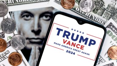 Elon Musk peers through an opening in a background of money next to a smartphone with the Trump-Vance 2024 election logo on the screen.