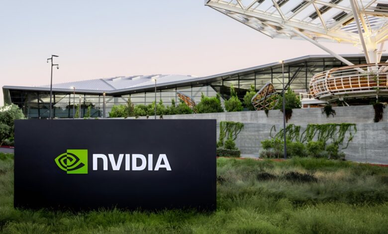 A sign with the NVIDIA logo stands in front of the company’s Voyager building, a modern glass and steel office structure surrounded by greenery.