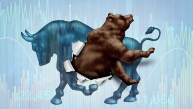 A bear bursts through the body of a bull, symbolizing a shift from a bull market to a bear market, with financial charts in the background.