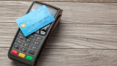 A blue credit card placed on a black payment terminal on a wooden surface.